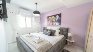 Un dormitorio con cama, mesita de noche, lámpara y un cuadro en la pared.