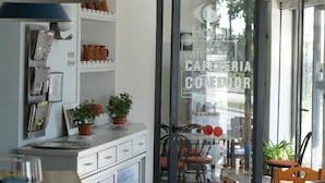 Una cocina moderna con encimera de madera, una lámpara colgante azul y una puerta de cristal que da a un comedor con sillas y mesa de madera.