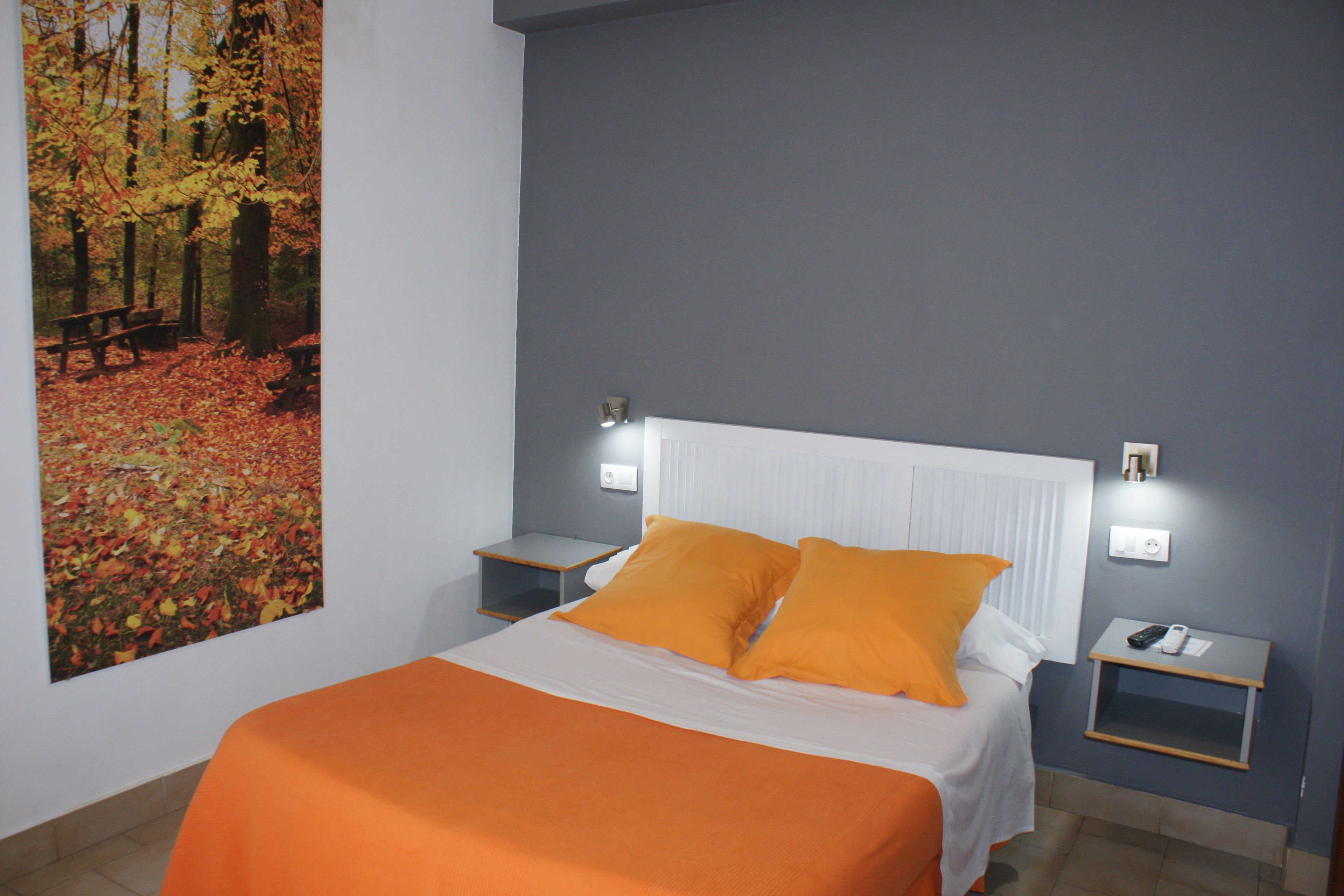A bedroom with a bed, nightstands, and a wall-mounted light fixture.