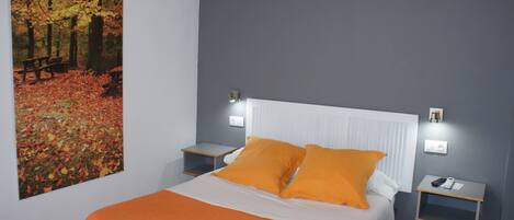 A bedroom with a bed, nightstands, and a wall-mounted light fixture.