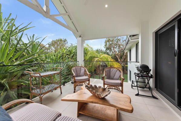 Enjoy al fresco dining on the spacious balcony with a wooden table, wicker chairs, and a barbecue grill.