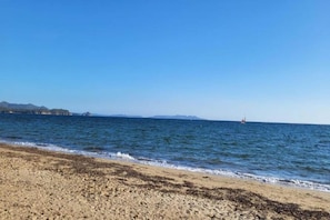 A beach with a clear sky, calm sea, and distant landforms. - Apartment in Cavalaire-sur-Mer near Beach (Cavalaire sur Mer)