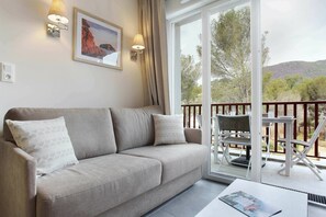 Ein modernes Wohnzimmer mit einer Couch, einem Tisch und einem Balkon mit Blick auf die Landschaft.