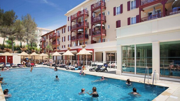 A swimming pool with multiple levels of balconies, sun loungers, and umbrellas. - Apartment in Cavalaire-sur-Mer near Beach (Cavalaire sur Mer)