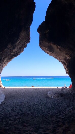 A beach with a clear view through a rock arch.