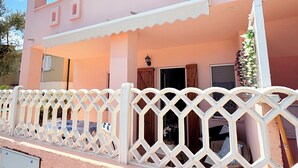 A pink building with a white balcony and lattice fence. - Apartment/ flat -Cala Gonone  - Casa dolce vista - Via delle Ginestre 20 (Cala Gonone)