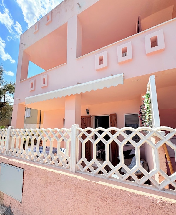 A pink building with a white balcony and lattice fence.