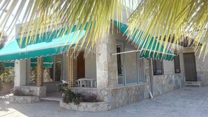 A stone building with a green awning, outdoor seating, and a stone planter with flowers. - Beautiful country house with private pool in Elche for 7 people. (elche)