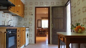 A kitchen with wooden cabinets, a stove, a washing machine, and a dining area with a table and chairs. - Beautiful country house with private pool in Elche for 7 people. (elche)