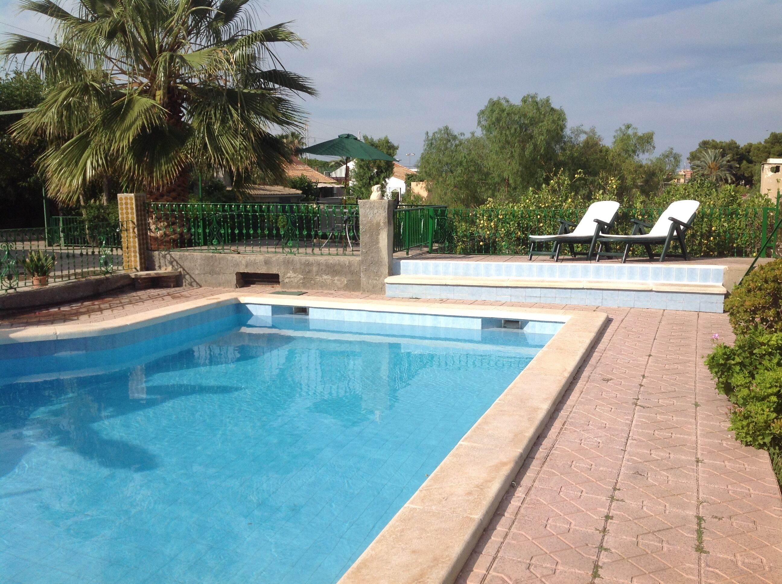 A rectangular swimming pool with a tiled edge, surrounded by a brick pathway.