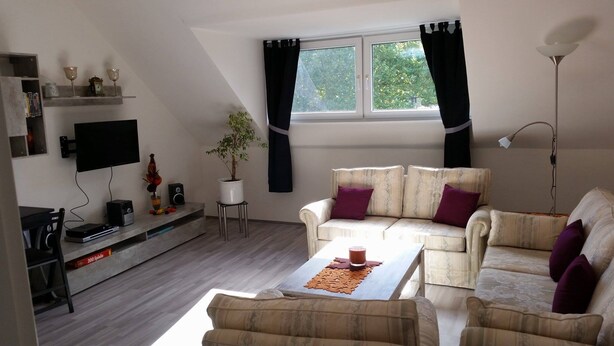 Un salon moderne comprenant un canapé, un téléviseur à écran plat, une table basse et une plante.