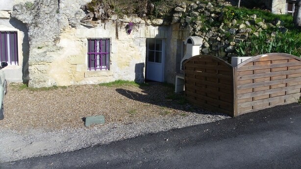 A stone building with a small entrance, a wooden gate, and a window with purple bars.