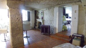 A spacious living area with a fireplace, a dining area, and a kitchen visible through an open doorway.