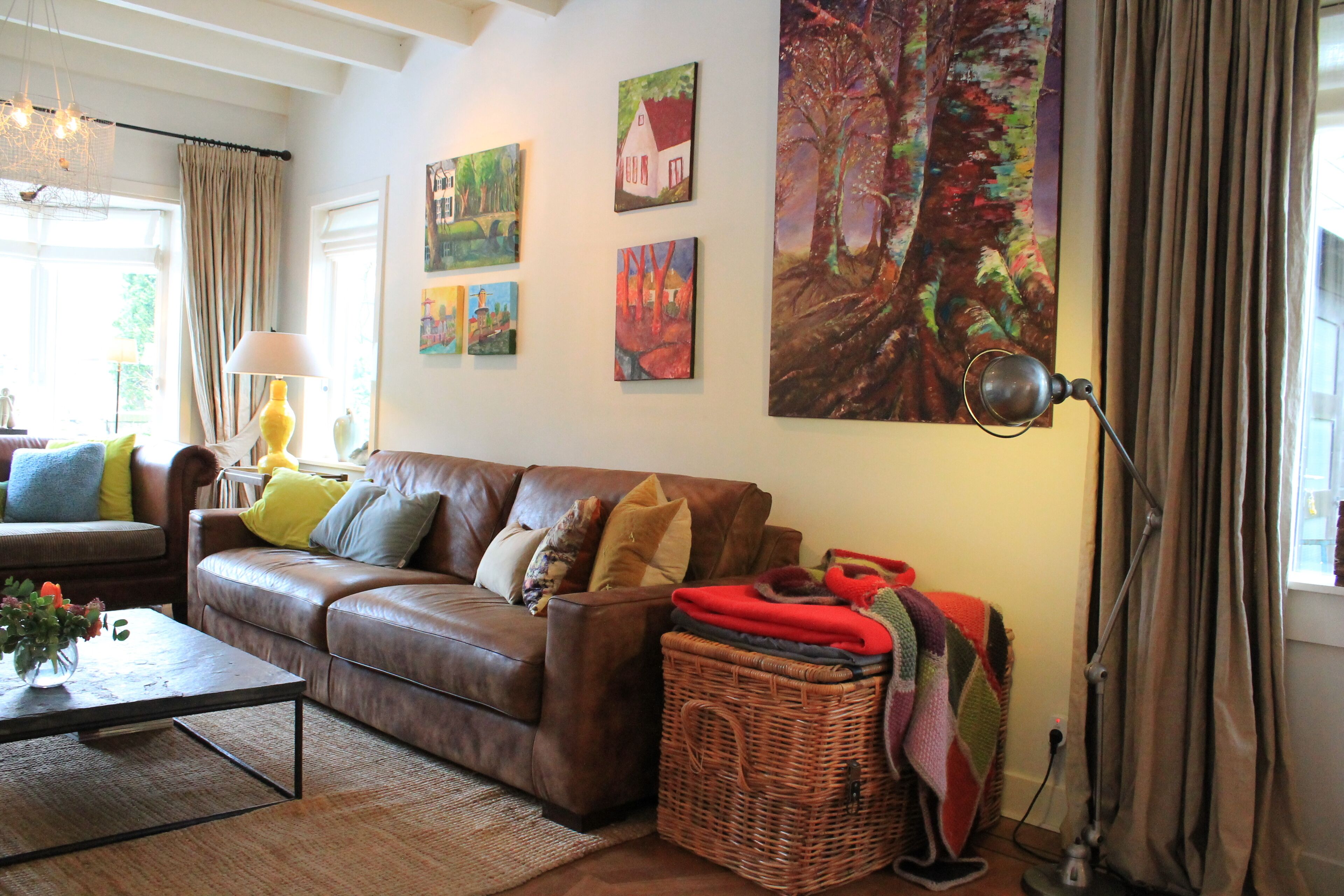 A living room with a brown leather sofa, a coffee table, and a large painting on the wall.