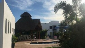 A resort with a thatched-roof structure, a pool area, and a well-maintained lawn. - departamento duplex increible! (Fraccionamiento Las Ceibas)