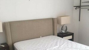 A hotel room with a bed, a nightstand with a lamp, and a shelf above the bed. - departamento duplex increible! (Fraccionamiento Las Ceibas)