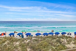 Een strand met parasols en mensen.