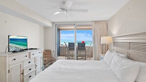 A hotel room with a bed, a television, a desk, a chair, and a view of the ocean. - Beach Front at Jetty East! One FREE Beach Chair Setup Each Day of Your Stay! (Destin)