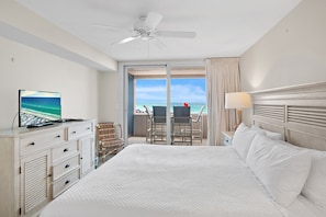 Une chambre d’hôtel équipée d’un lit, d’une télévision, d’un bureau, d’une chaise et offrant une vue sur l’océan.