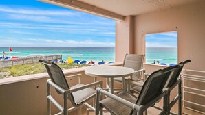 A balcony with a view of the beach, a round table, and two chairs. - Beach Front at Jetty East! One FREE Beach Chair Setup Each Day of Your Stay! (Destin)