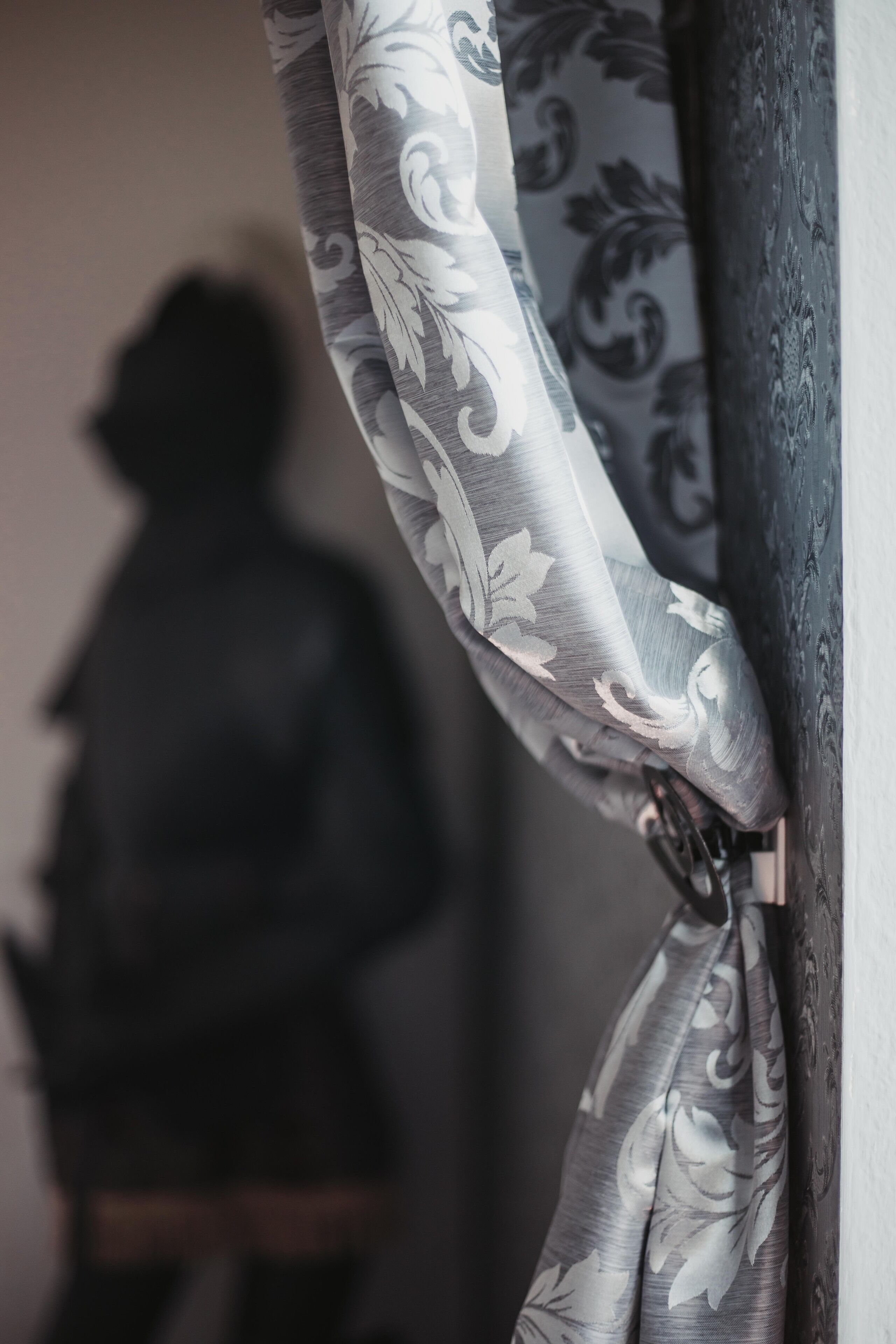 A curtain with a floral pattern tied to a dark-colored door frame.