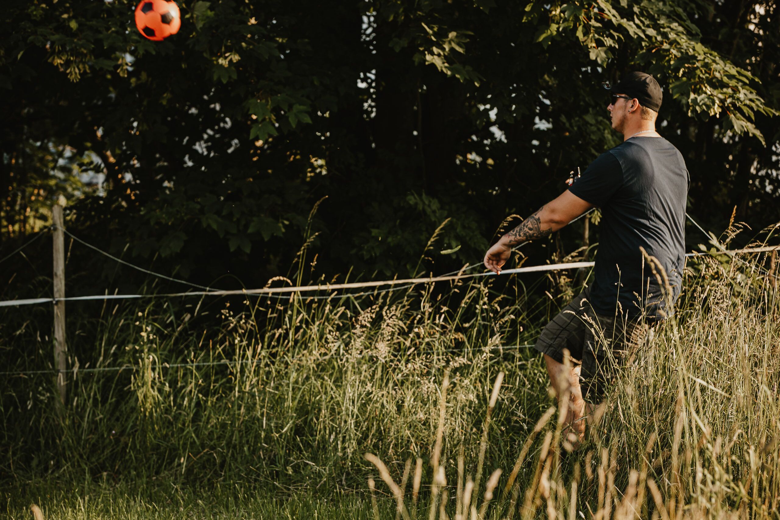 A man playing soccer in a grassy field with trees in the background.