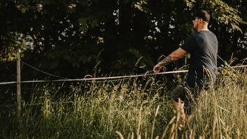 Un hombre jugando al fútbol en un campo cubierto de hierba, con árboles al fondo.