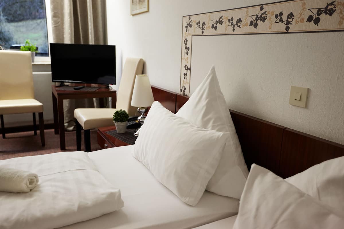Une chambre d’hôtel équipée d’un lit, d’une télévision, d’un bureau, d’une chaise et d’une lampe.