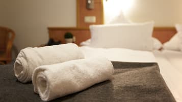A neatly made bed with white towels and a dark blanket.