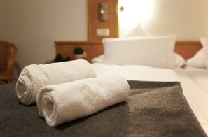 A neatly made bed with white towels and a dark blanket. - Hotel Zur Burg Sternberg (Extertal)