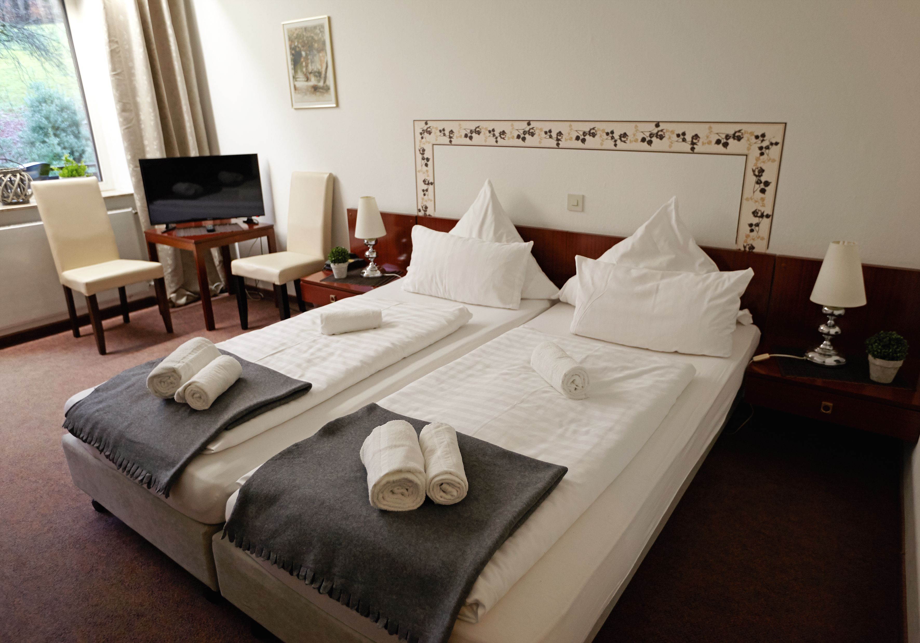 Una habitación de hotel con una cama grande, dos mesitas de noche, un televisor, una silla y un escritorio.
