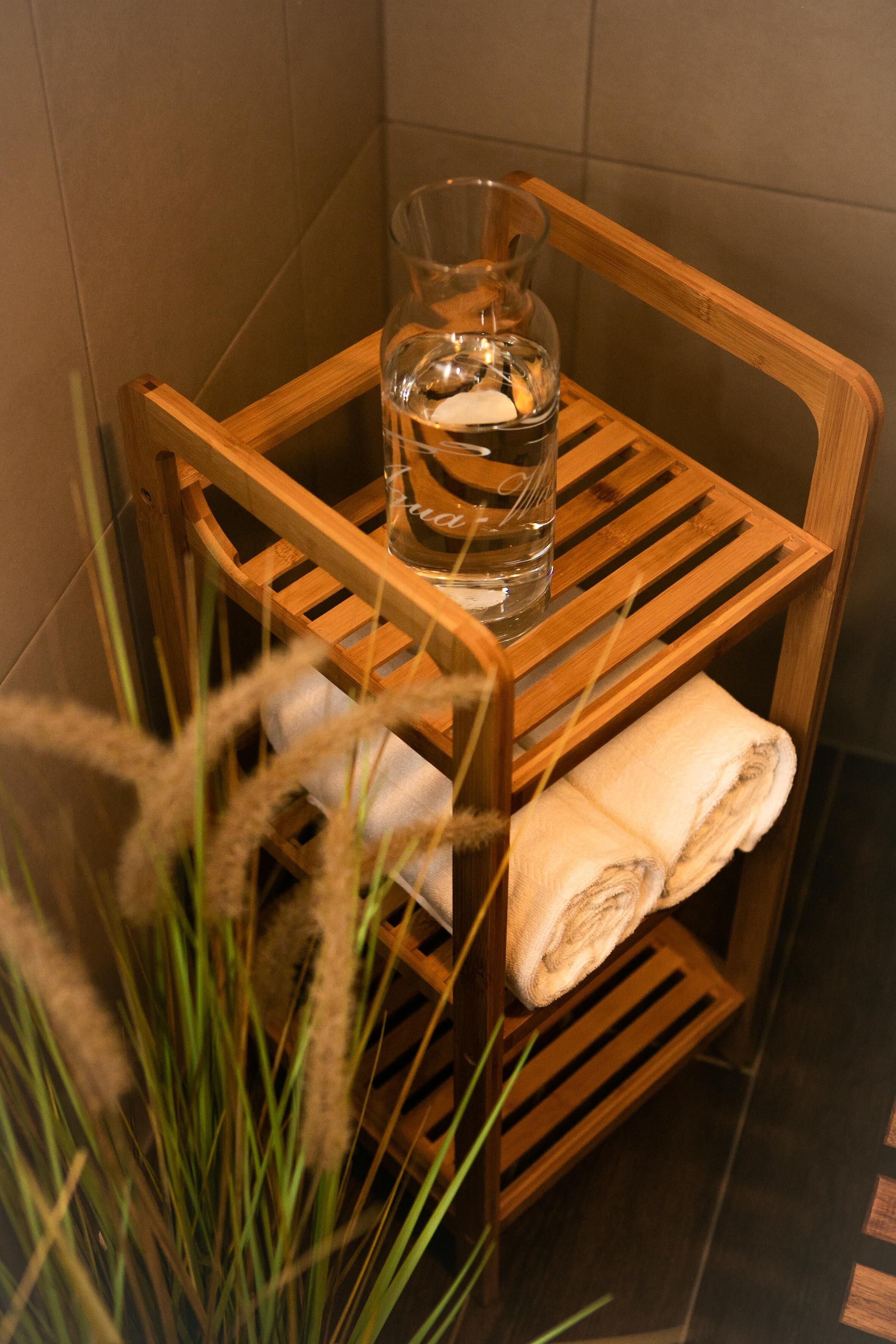 A wooden shelf with a glass pitcher and a folded towel.