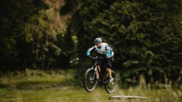 Una persona pedala su un sentiero erboso, con alberi sullo sfondo.