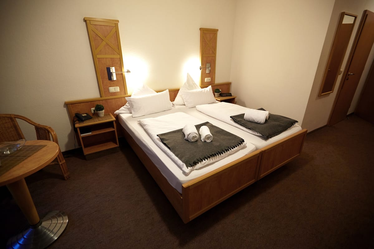 Une chambre d’hôtel avec un lit double, deux tables de chevet, une chaise, une petite table et un miroir.