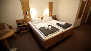 A hotel room with a double bed, two bedside tables, a chair, a small table, and a mirror.
