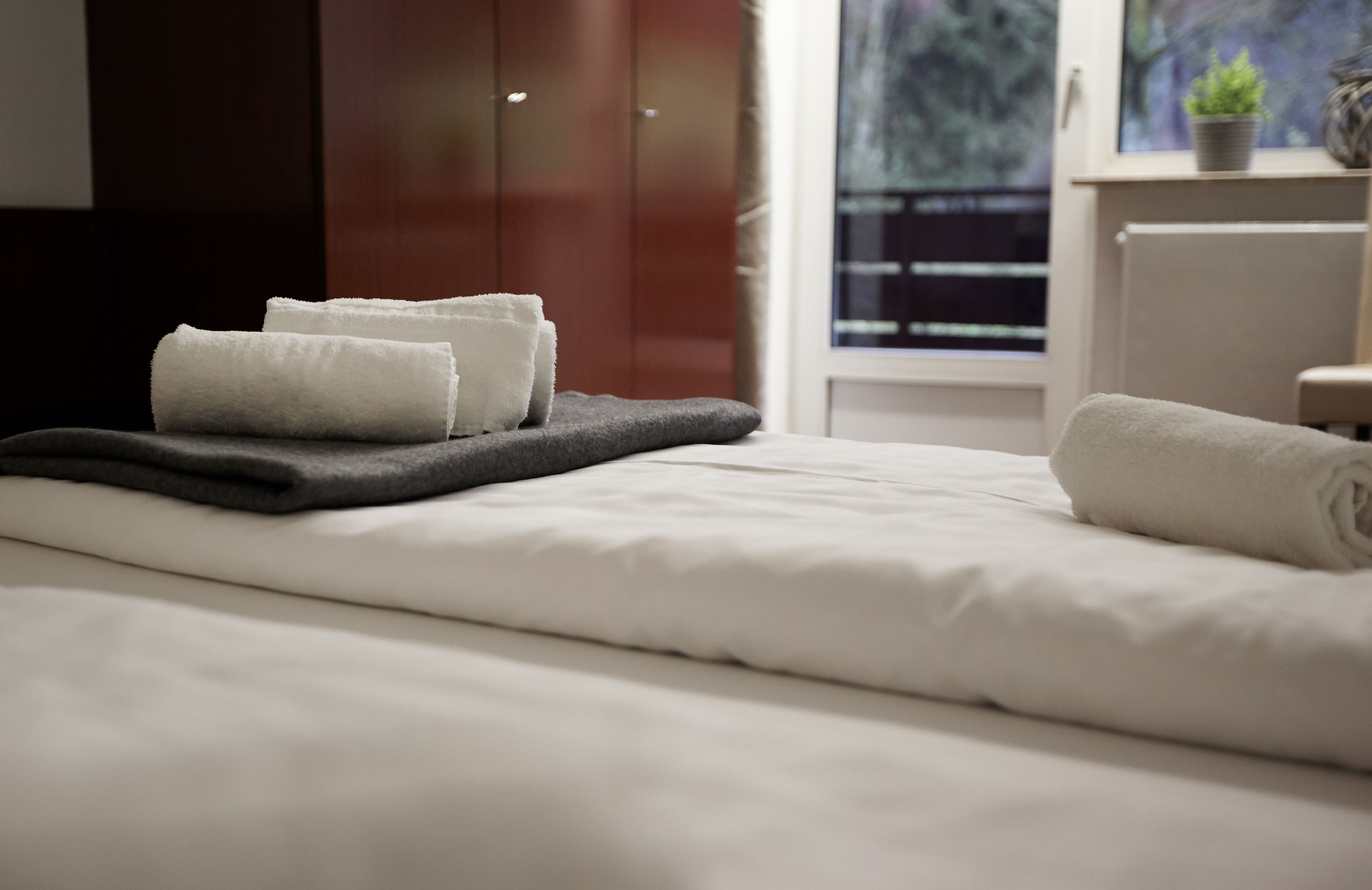 A neatly made bed with white linens and a dark gray blanket.