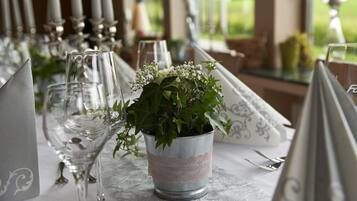 Una mesa dispuesta para un evento formal, con cubertería de cristal, vajilla y un centro de mesa con flores.