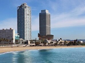 Un paisaje urbano costero con modernos rascacielos, una playa y cielo despejado.