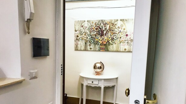 A room with a white door, a small white table with a globe, and a decorative wall piece. - Casa G&G Pignasecca 2 in the heart of Naples (Napoli)