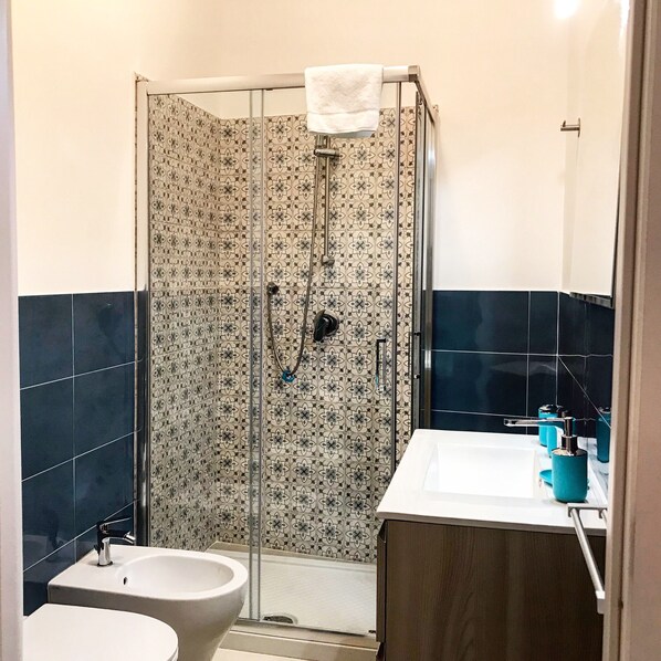 Une salle de bain avec douche, toilettes et lavabo.
