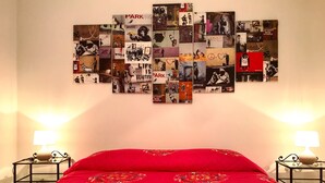 A hotel room with a bed, two nightstands, and a wall art collage. - Casa G&G Pignasecca 2 in the heart of Naples (Napoli)