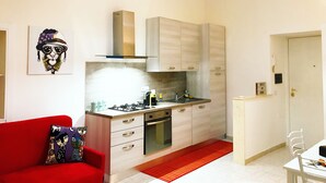 A compact kitchen with modern appliances, a red sofa, and a dining area. - Casa G&G Pignasecca 2 in the heart of Naples (Napoli)