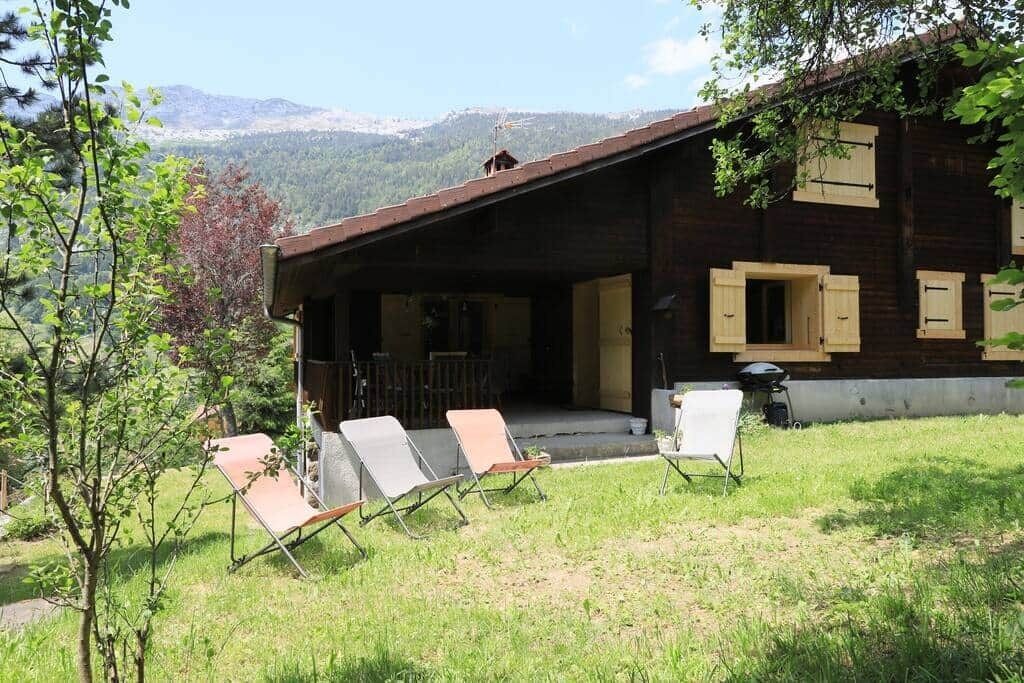 Une cabane en bois dotée d’un porche abrité, de meubles d’extérieur et offrant une vue sur les montagnes.