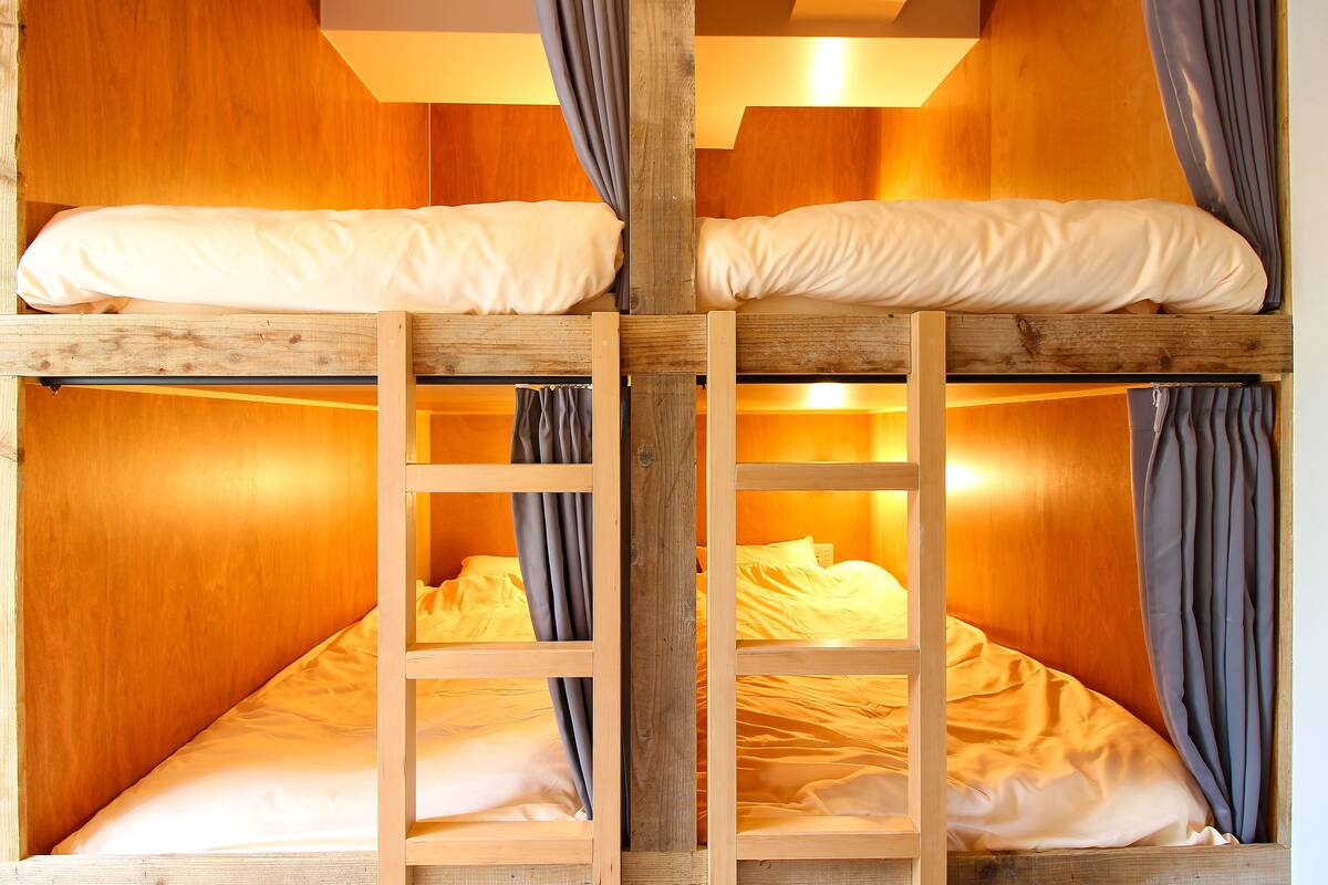 Habitación con literas, paredes de madera y cortinas.