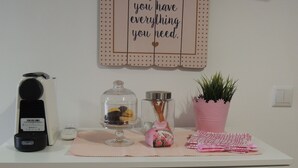 Un comptoir de cuisine avec une machine à café, un bocal en verre avec un couvercle en métal, une plante en pot et un panneau décoratif accroché au mur.