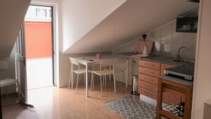 Une cuisine de taille réduite comprenant un coin repas, un petit évier et une cuisinière.