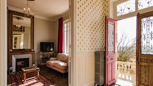 A living room with a fireplace, sofa, television, and a patterned wall. - Stylish Mansion in Savignac (Savignac-Ledrier)