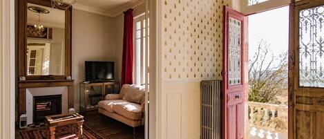 A living room with a fireplace, sofa, television, and a patterned wall.
