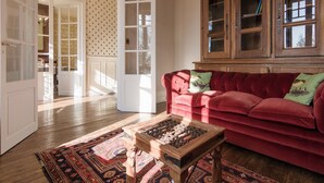 A living room with a red sofa, a wooden coffee table, and a patterned rug. - Stylish Mansion in Savignac (Savignac-Ledrier)