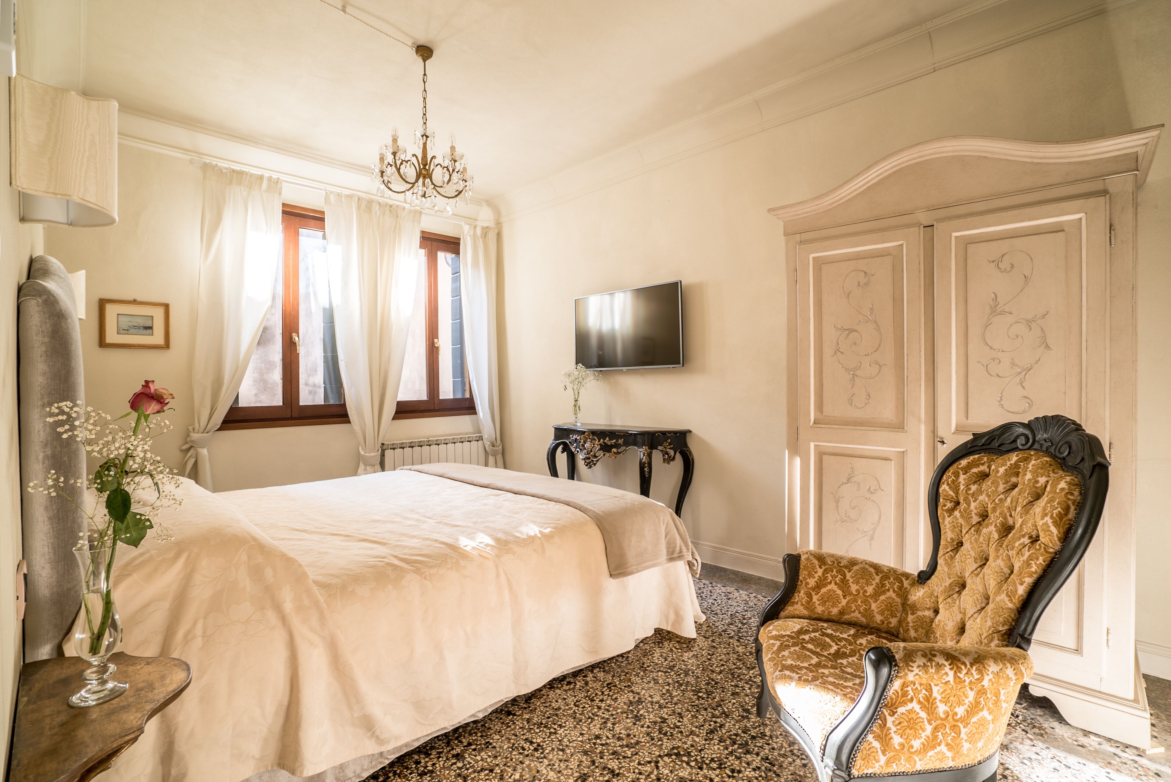 A bedroom with a bed, a chair, a TV, and a dresser.